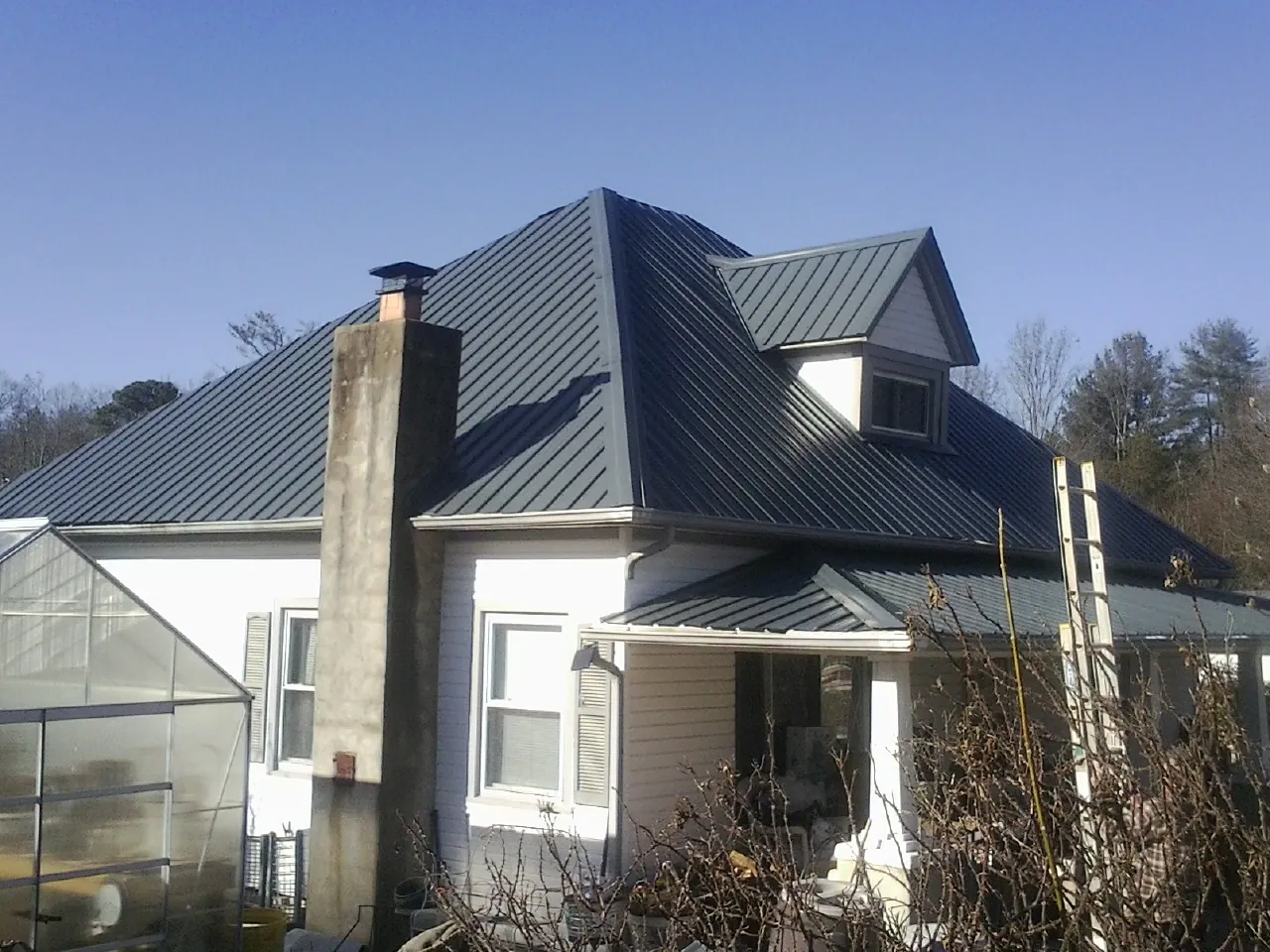 Dark blue standing seam metal roof on a white farmhouse with dormer — Slate & Tile Roof Repair by Roofing Brothers in Penn