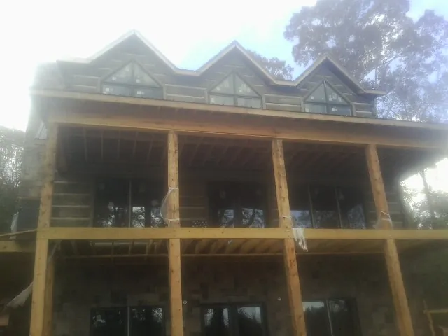 Dormers and porch framing on a large log home under construction — Roof Coating work by our crew in Penn