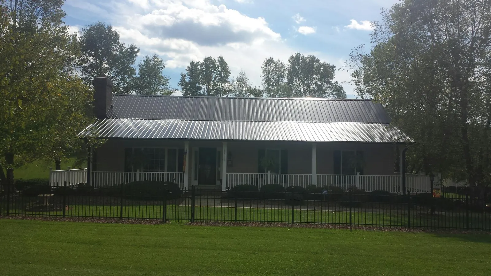 Gray metal roof on a brick ranch with a full width front porch — Gutter Guard Installation work by our crew in Penn