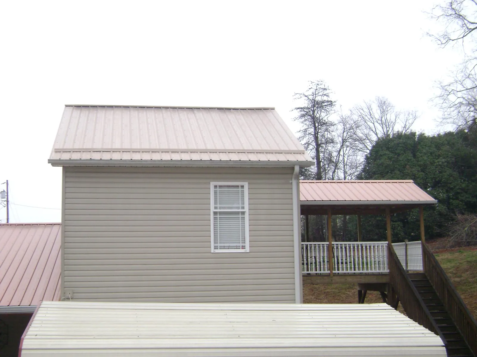 Tan metal roofs on a two story addition and attached porch, from a Roof Replacement job in Penn