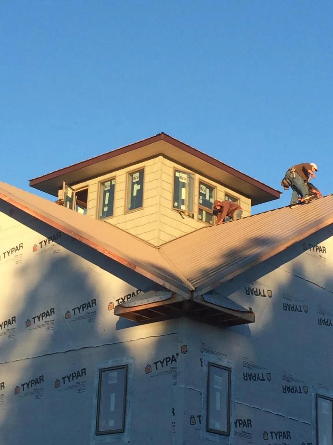 Roofers working around a rooftop cupola on a new metal roof at sunset — Roof Waterproofing in Penn by Roofing Brothers